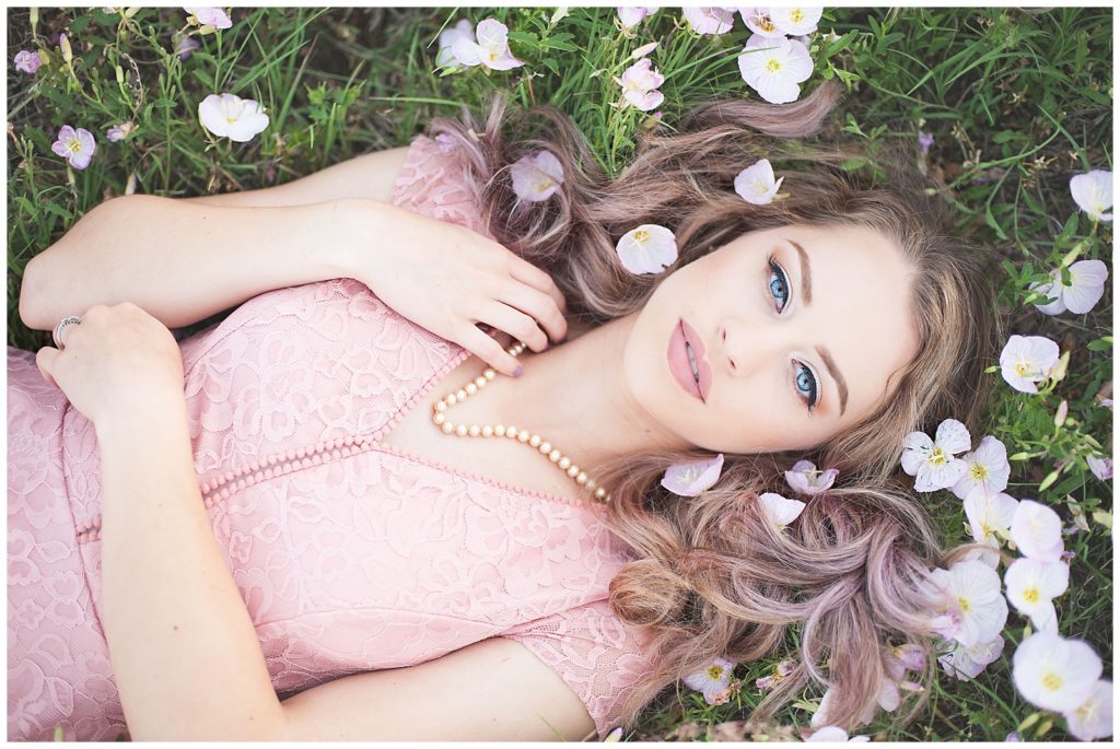 high school senior girl lying in pink flowers in Wichita, KS