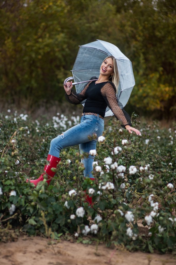 High School senior photos Wichita, KS girl in cotton field with red boots and transparent umbrella