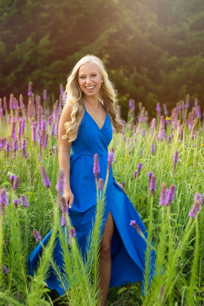 high school senior in field of flowers wearing bright blue dress. Kim Stiffler Photography