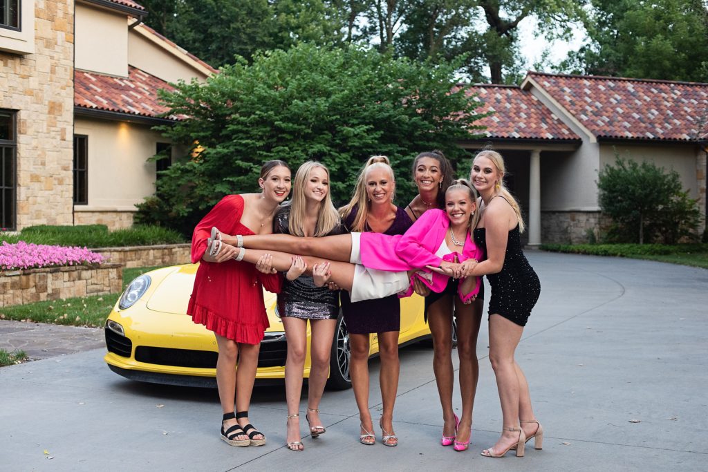 High School girls dressed up posing in front of yellow Porsche