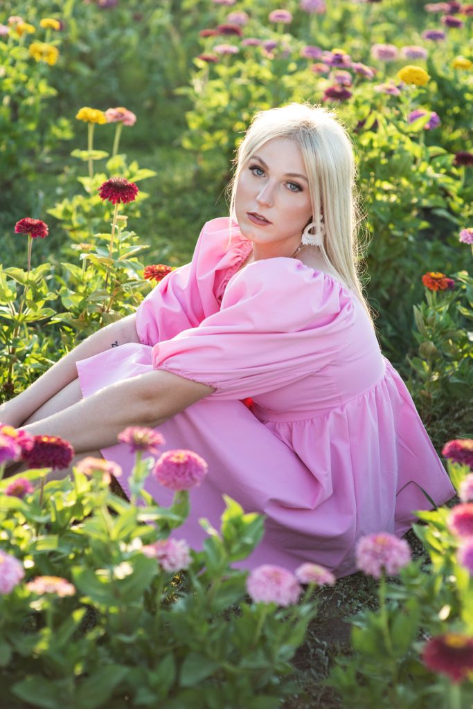 high school senior girl in. pink dress sitting in field of zinnias senior pictures