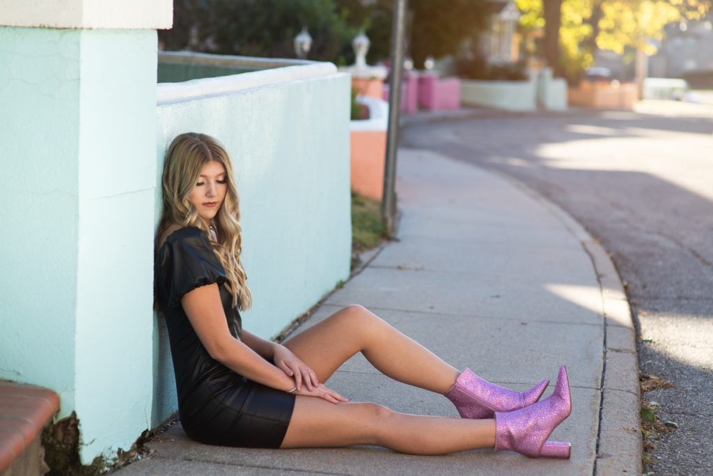 high school senior in black dress and pink boots in front of blue house.  Senior portraits Kim Stiffler Photography