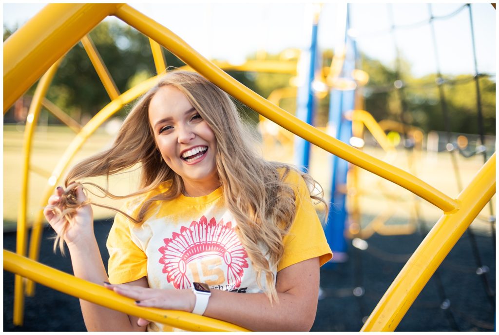 high school senior girl in yellow and red KC Chiefs shirt, yellow. playground bars, senior pictures