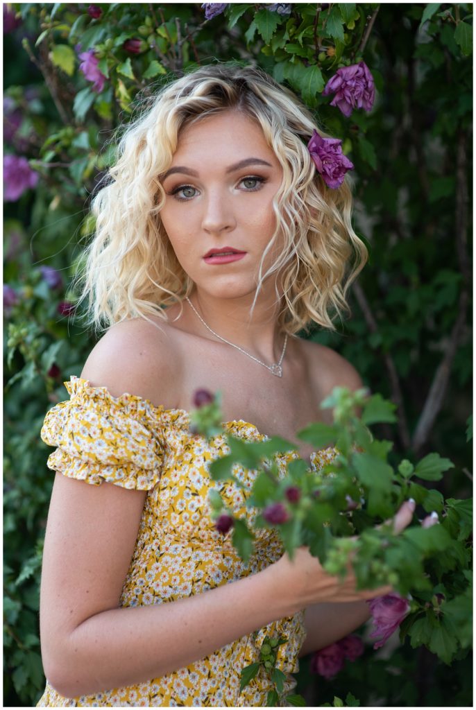 high school senior in floral bush with yellow dress
