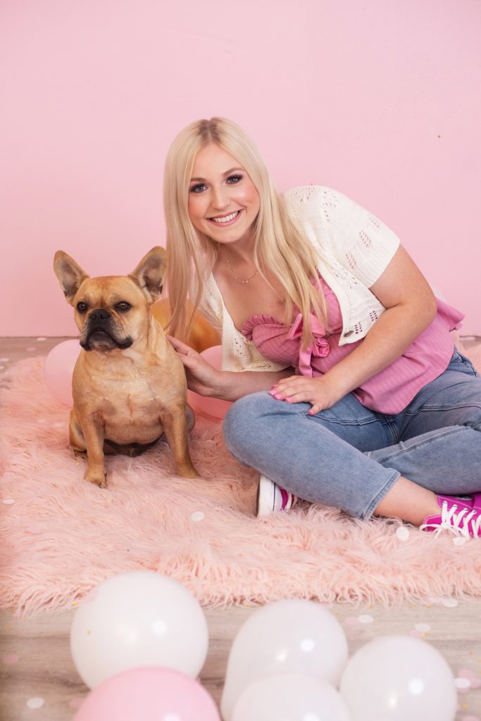 girl and french bulldog posing in front of pink background
