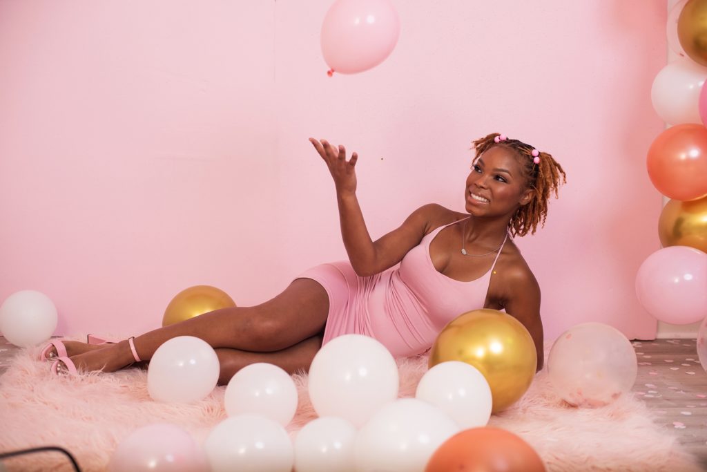 girl lying down around pink balloons