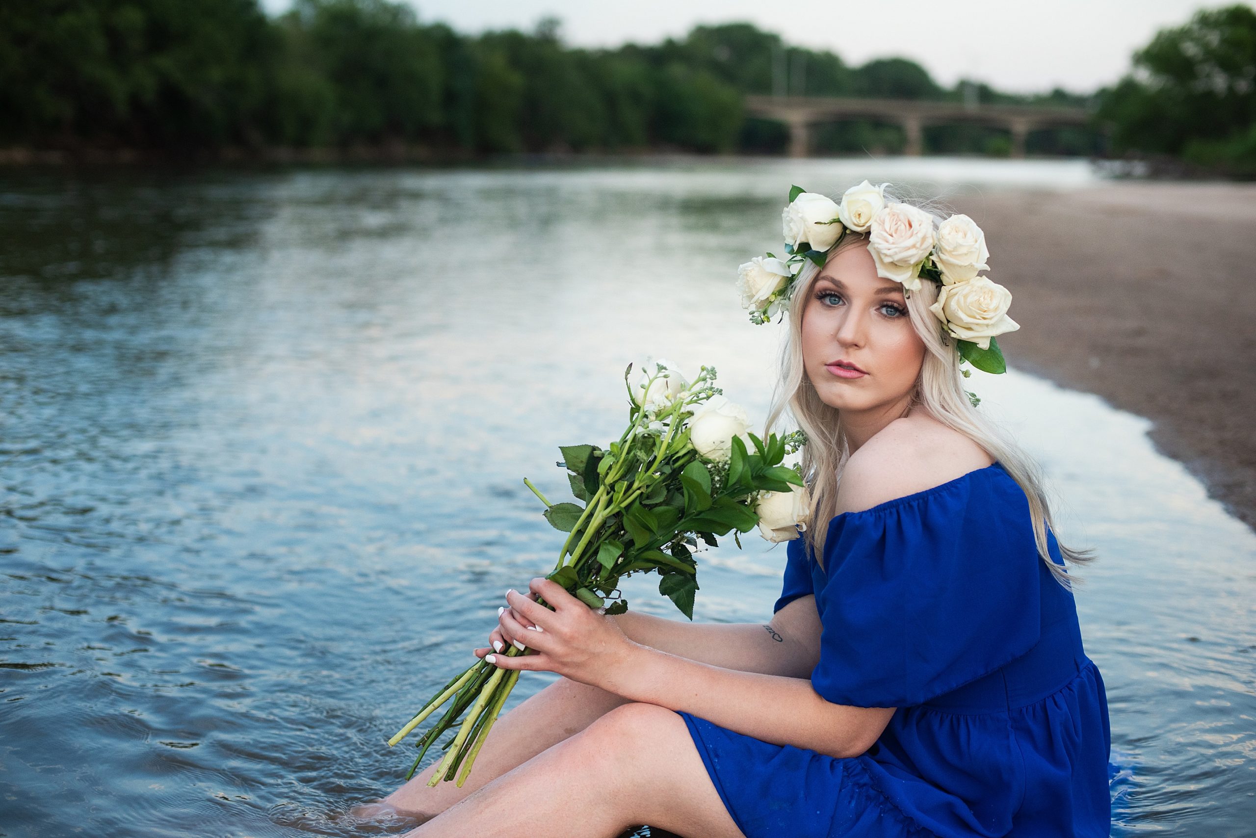 girl in blue dress sitting in water with a floral crown