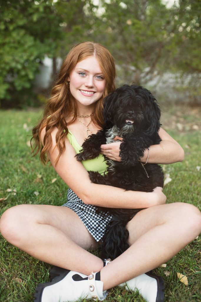 girl senior pictures with small black dog