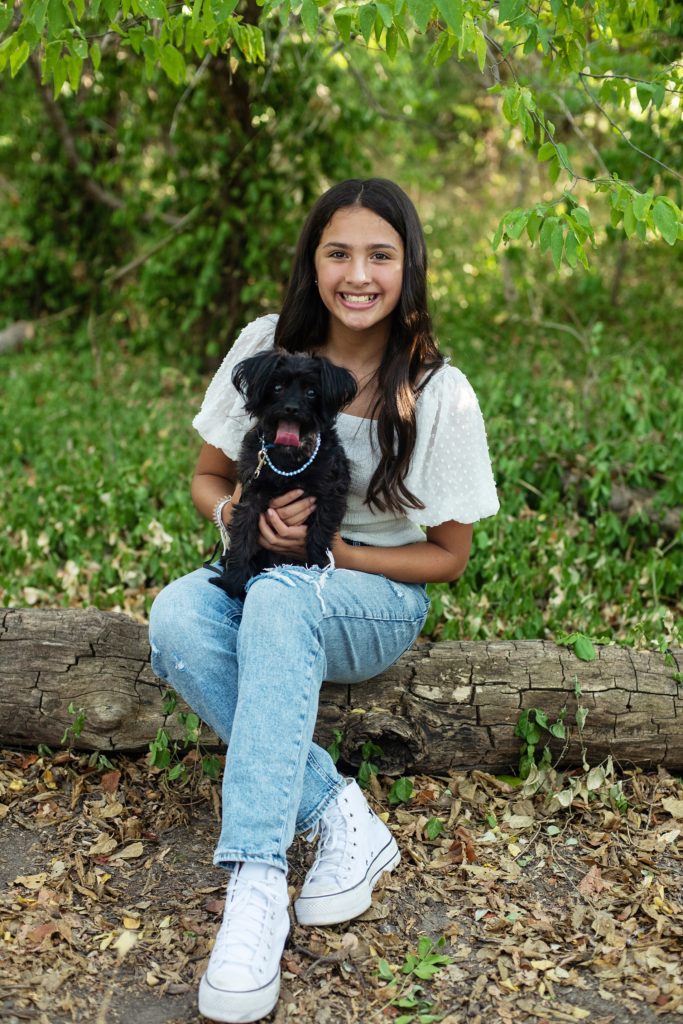 girl holding black puppy in a park