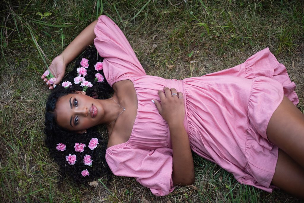 high school senior girl in pink dress with lying down with flowers in her hair.  Kim Stiffler Photography