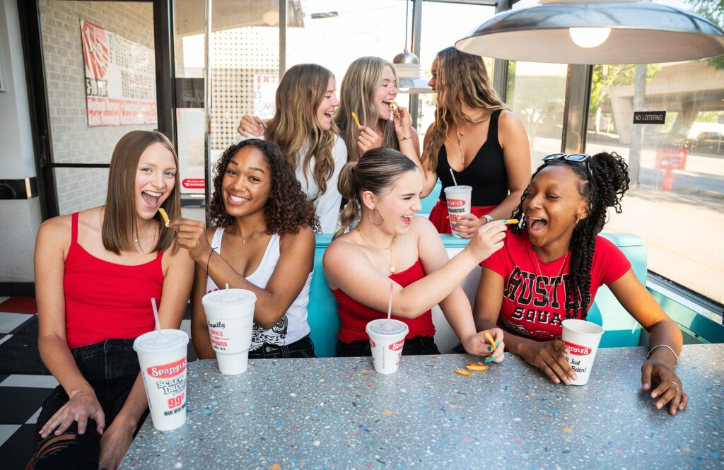 group of high school seniors at Spangles dressed in red, white and black feeding each other fries