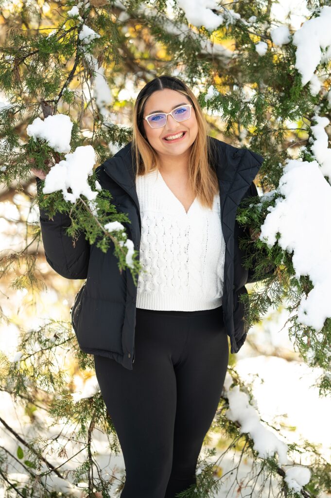 high school senior girl in snow covered Pine tree photoshoot