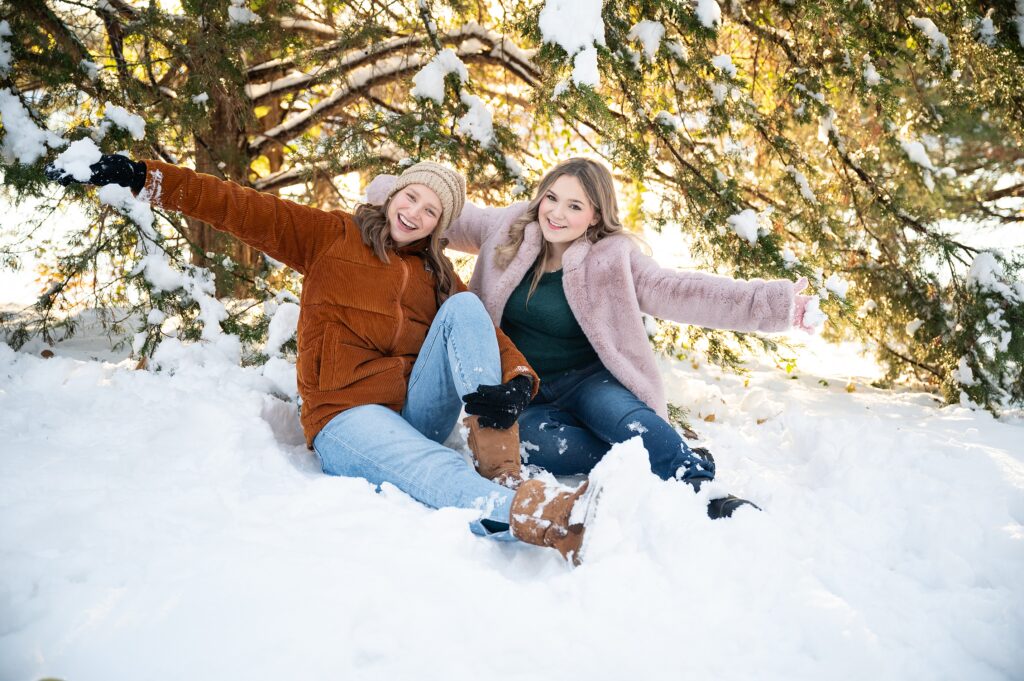 Two high school senior girls playing in snow for a photoshoot.