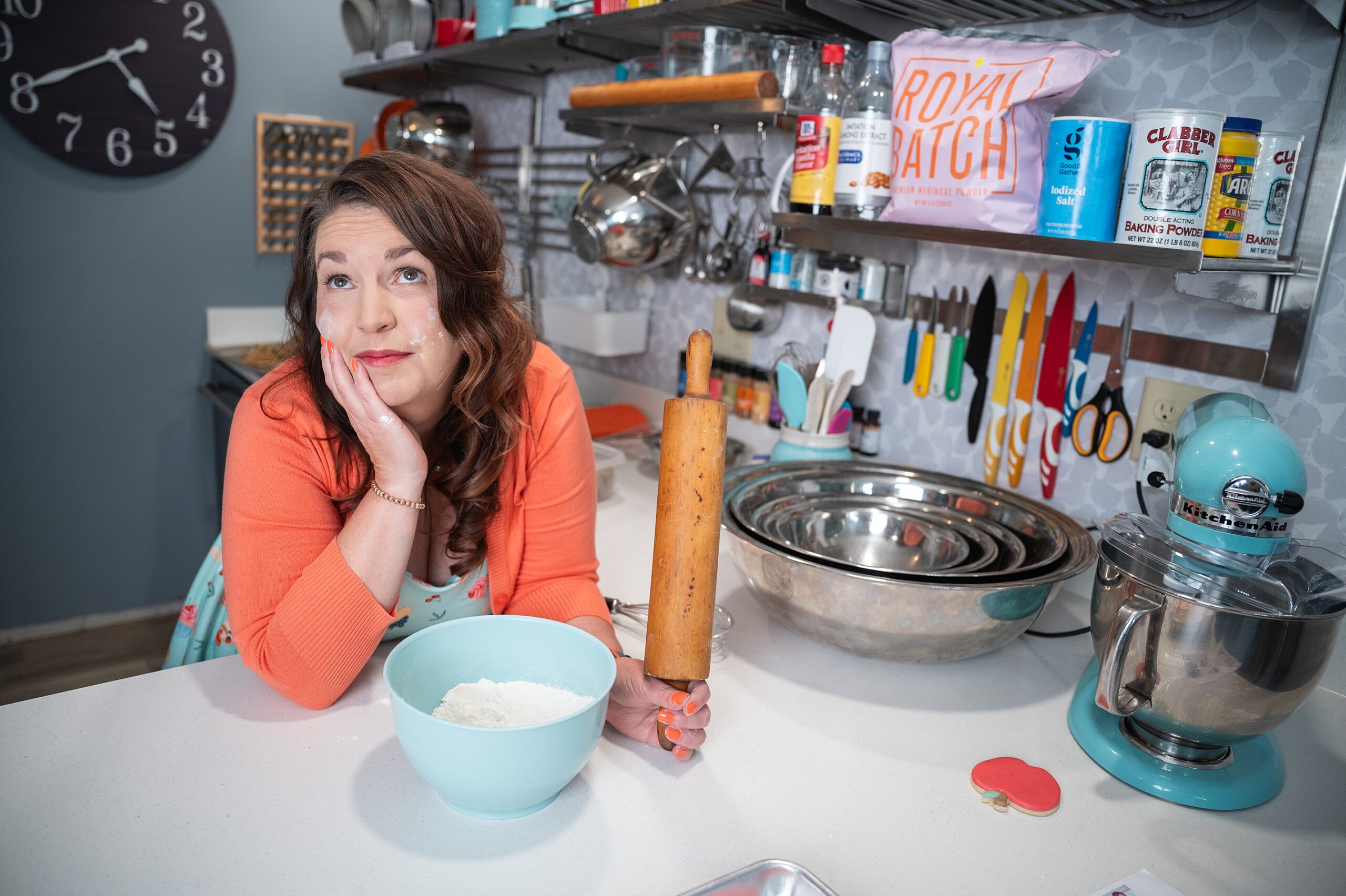 Baker in her kitchen with mixing bowl and rolling pin, and flour on her face.